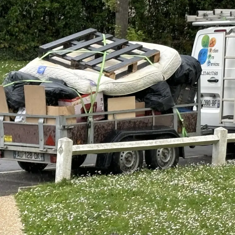 Remorque chargée de mobilier et d’encombrants, garée devant le camion Action Pro Services