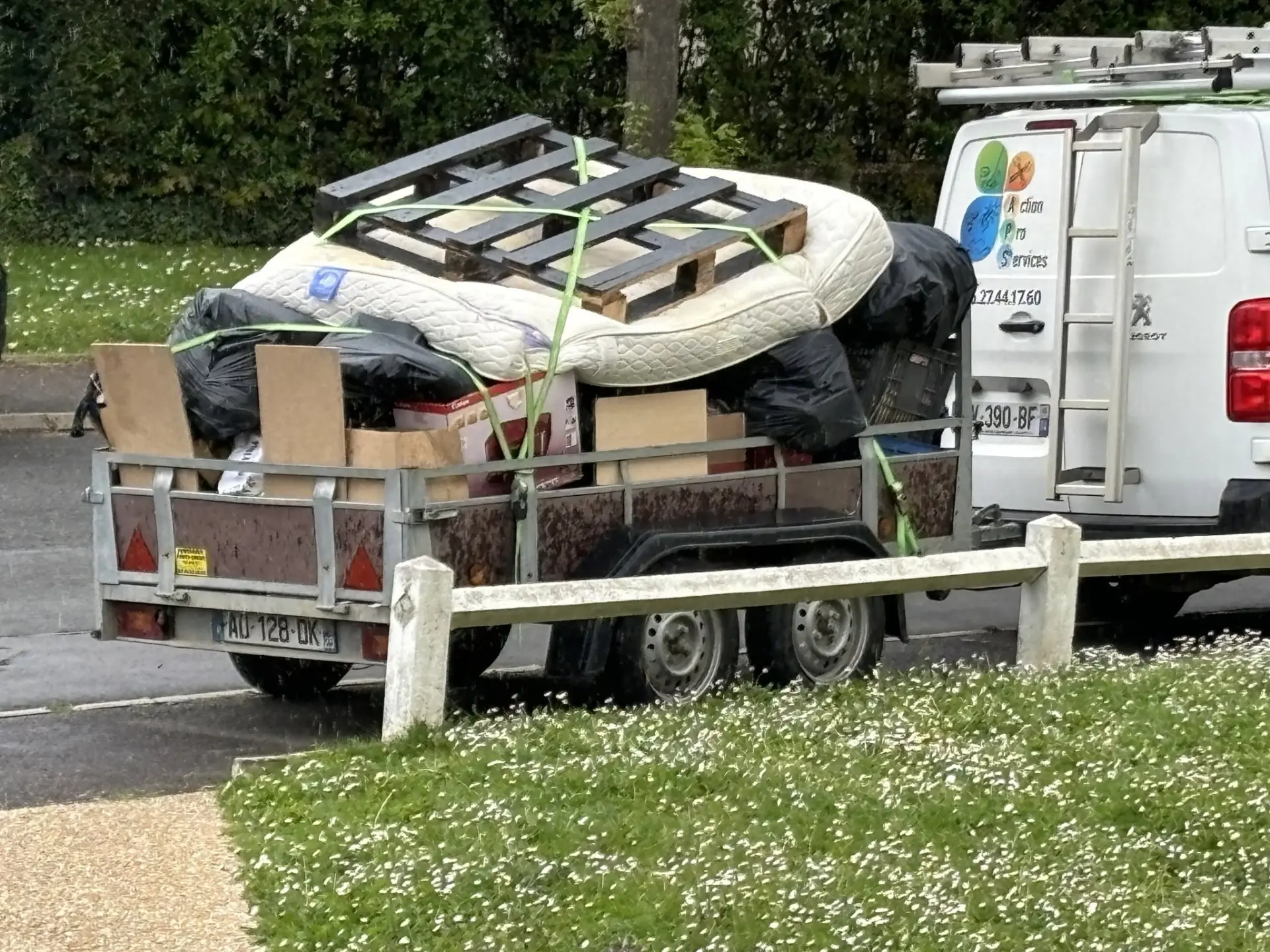 Remorque chargée de mobilier et d’encombrants, garée devant le camion Action Pro Services