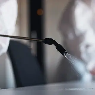 Technicien en combinaison de protection pulvérisant un traitement sur une surface